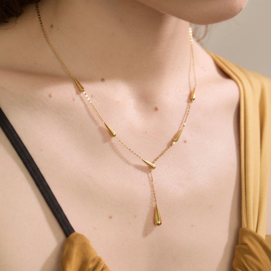 PRO RAY AIRA gold-tone necklace with drop-shaped accents, delicate chain, worn by a model.