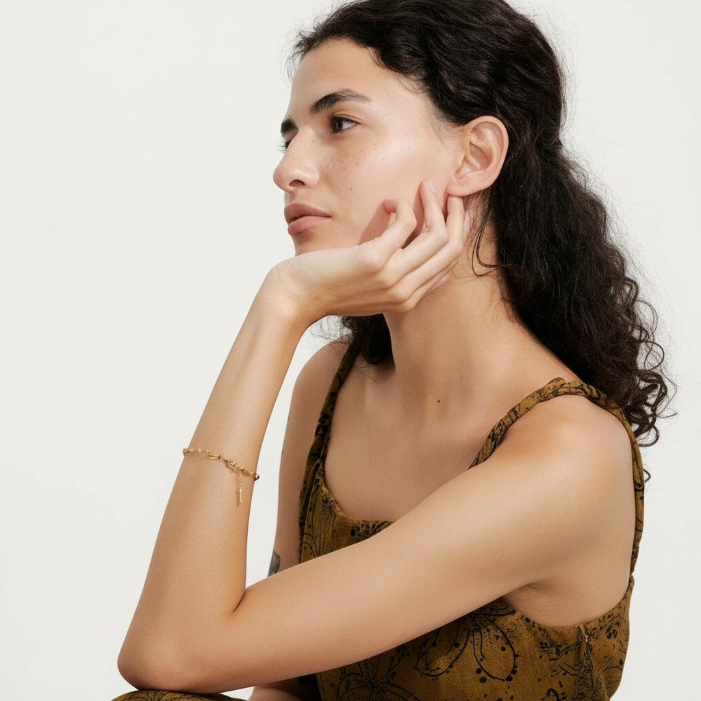 PRO RAY ELVARA gold-tone bracelet with a delicate wave chain and textured detailing on a woman's wrist.