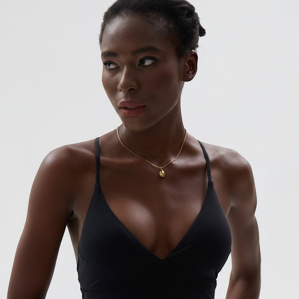 PRO RAY TELYA necklace with sculptural gold pendant on a delicate chain, worn by a model.