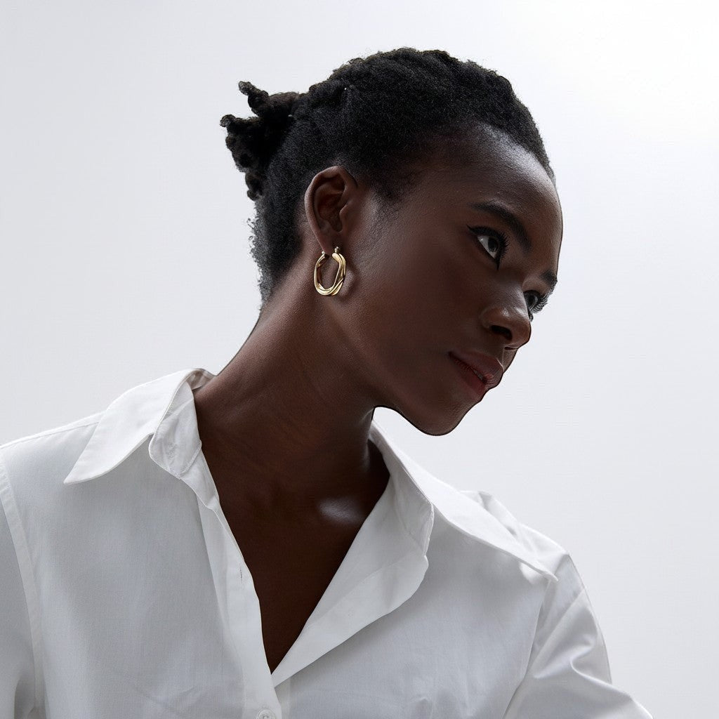 PRO RAY ZARIA gold twisted hoop earrings with sculptural silhouette, 31mm diameter, worn by a model.